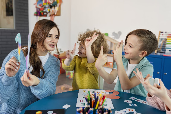 Children learning and interacting with a childcare educator in a daycare classroom